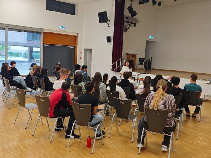 Ein Teil des Jahrgang 9 hört in der Aula der Autorin Frau Flacke zu. 