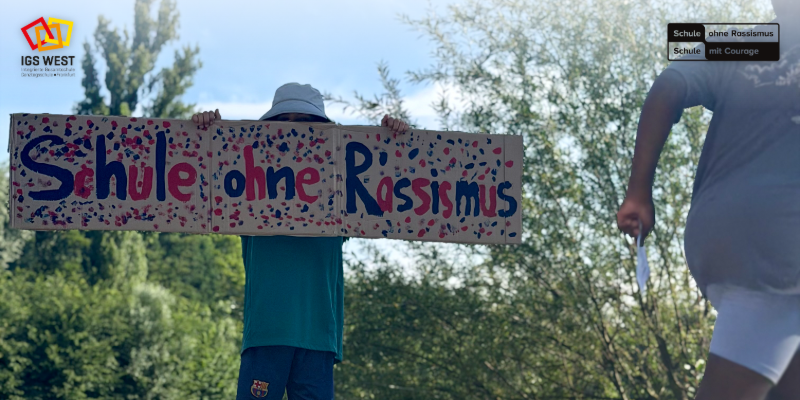 Das Bild zeigt ein Schild, das während des Spendenlaufs hochgehalten wurde. Es steht darauf: Schule ohne Rassismus. 